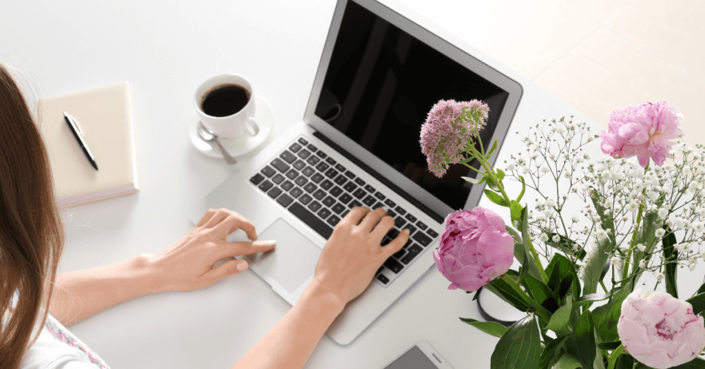 Woman entrepreneur working on laptop with flowers and coffee – SEO tool for women entrepreneurs