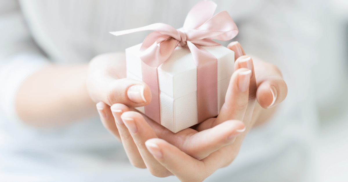 Aesthetic Christmas Gift for Women 40+ | Holiday Guide Hands holding a small aesthetic Christmas gift with a pink ribbon, perfect for women 40+